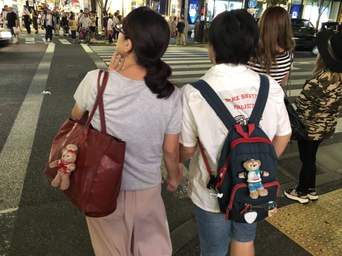 Två japanska kvinnor med kramdjur på sina väskor